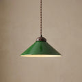 Green enamel conical pendant light with a bronze fixture hanging against a textured beige background.
