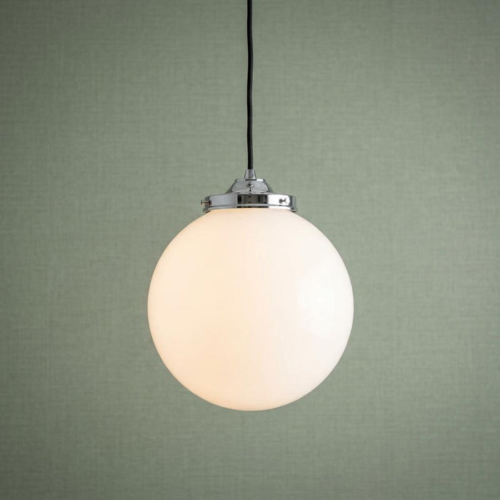 Opal glass globe pendant light with chrome gallery and black cable, illuminated against a sage green wall.