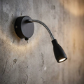 Black adjustable LED reading light with a toggle switch and flexible chrome arm mounted on a textured concrete wall.