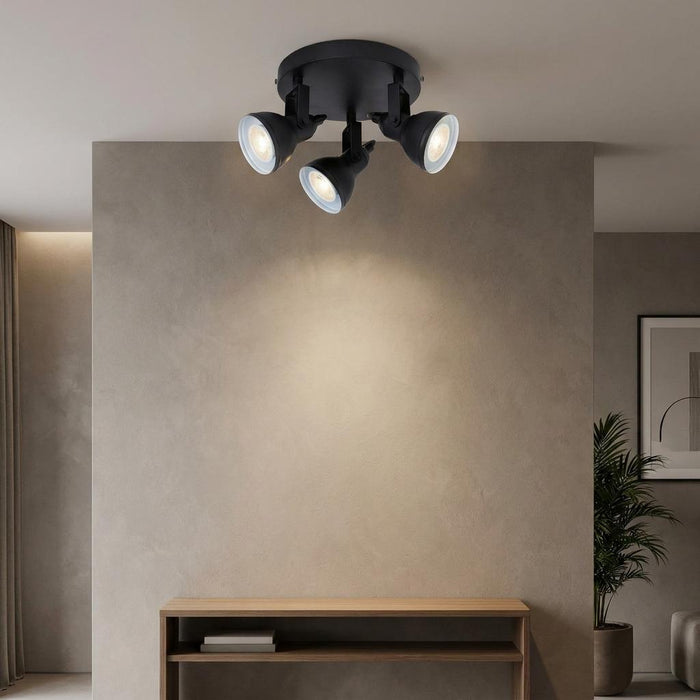 Black Focus 3-light adjustable ceiling spotlights illuminating a beige wall in a modern living room.