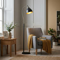 Pewter and black floor lamp with a curved neck, standing beside a grey armchair in a light living room.