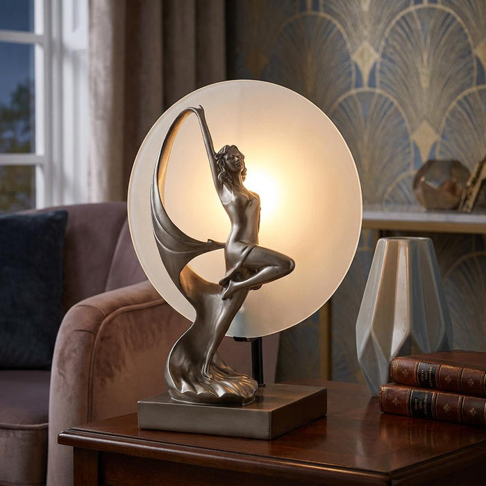 Art Deco bronze figurine lamp of a dancing woman silhouetted against a glowing circular frosted glass backplate.