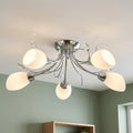Modern five-light chrome ceiling fixture with frosted glass shades and crystal accents against a green wall.