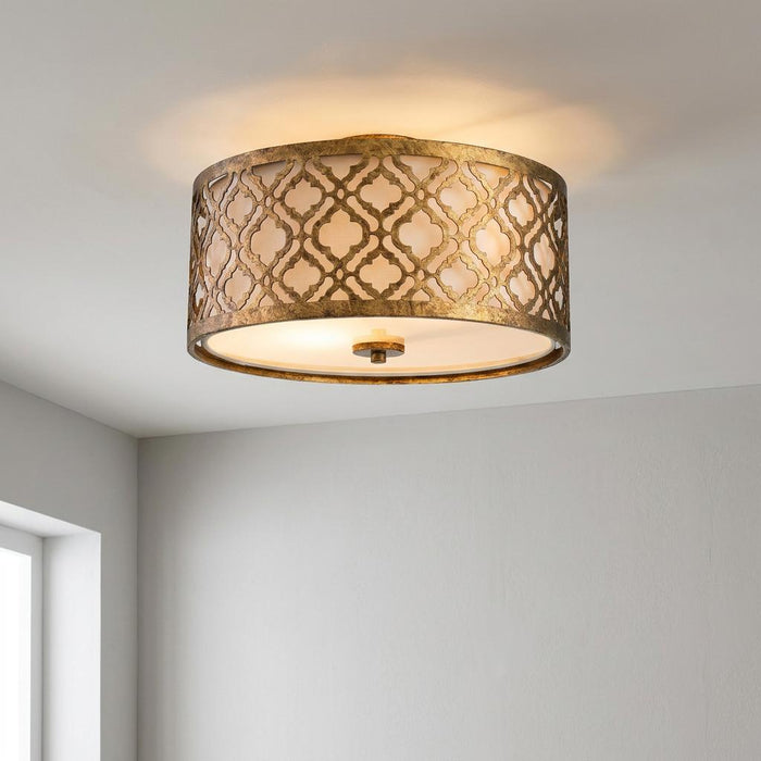 Gilded Nola Arabella flush ceiling light featuring an intricate gold lattice pattern over a white drum shade.