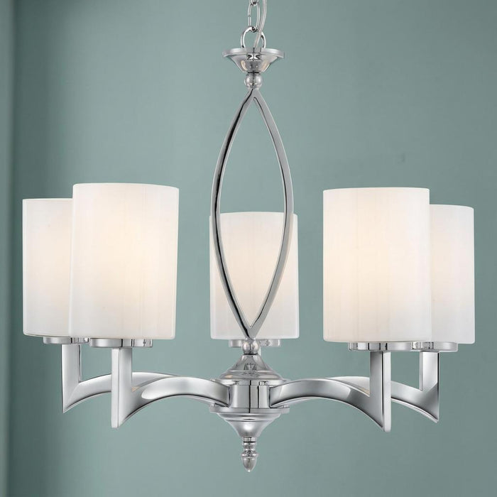 Five-light chrome ceiling pendant with white cylindrical glass shades set against a pale blue wall.