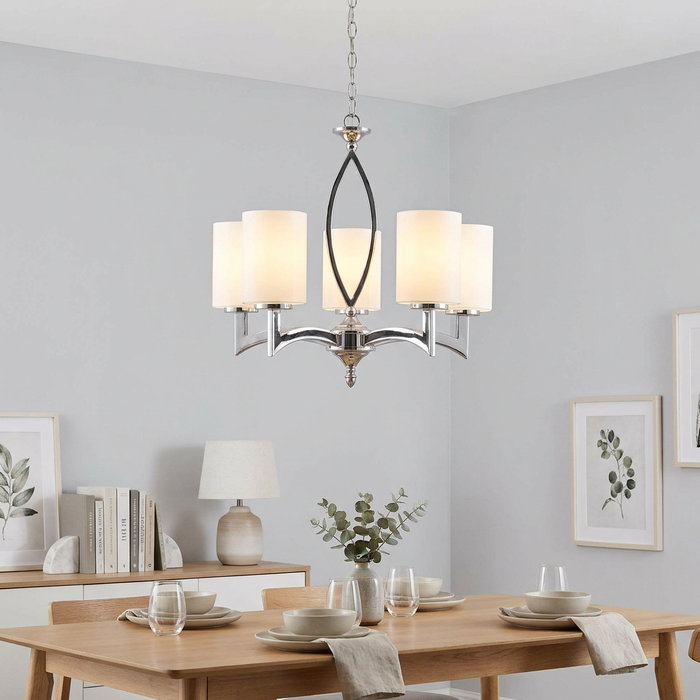 Five-light chrome ceiling pendant with cylindrical white glass shades hanging above a modern dining room table.