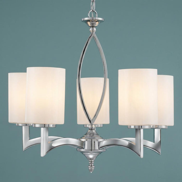 Five-light chrome pendant chandelier with white cylindrical glass shades on a teal background.