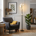 Gio black and brass LED mother and child floor lamp illuminating a cozy living room with a grey armchair.