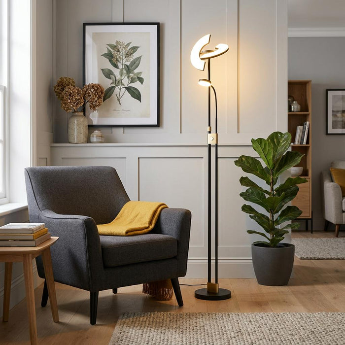 Gio black and brass LED mother and child floor lamp illuminating a cozy living room with a grey armchair.