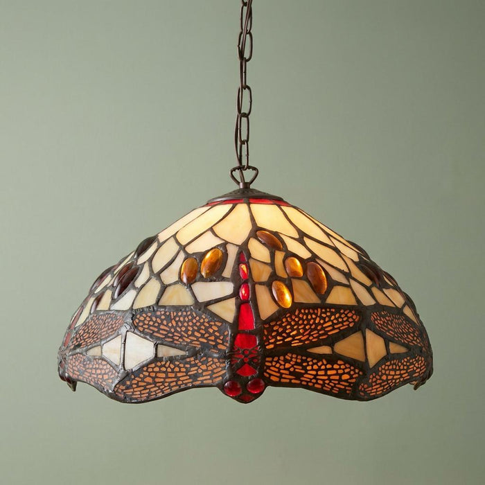 Golden Dragonfly small Tiffany pendant light with intricate red and amber stained glass shade hanging against a green wall.