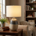 Grange Park grey and brown ceramic table lamp with a cream shade on a wooden side table in a living room.