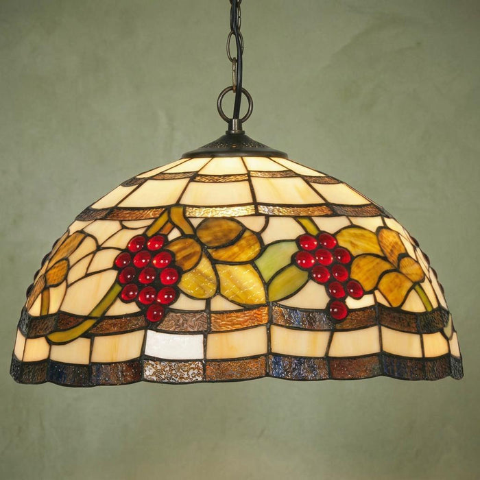 Grapes Tiffany pendant light with red glass beads and green leaves hanging against a textured green background.
