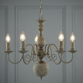 A Greythorne 5-light textured grey chandelier with a rustic finish and candle-style bulbs against a paneled wall.