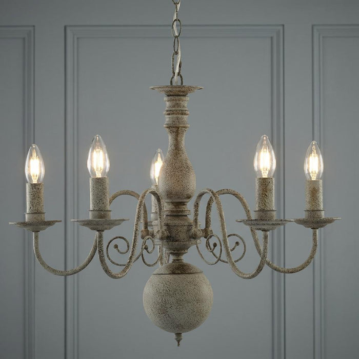 A Greythorne 5-light textured grey chandelier with a rustic finish and candle-style bulbs against a paneled wall.