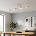 White and brushed brass four-light LED spotlight bar illuminating a modern dining room.