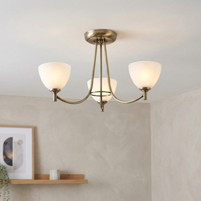 Three-arm antique brass Art Deco ceiling light with frosted glass shades illuminated in a modern room.