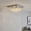 Modern square chrome flush ceiling light with tiered crystal glass spheres, illuminated against a white ceiling.
