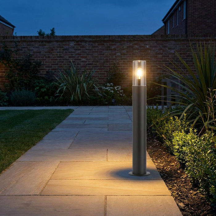 Hayden bollard light with a clear glass shade illuminating a stone patio path at dusk.