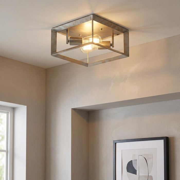 Industrial square flush ceiling light with a brushed silver and gold metal frame and two glowing filament bulbs.