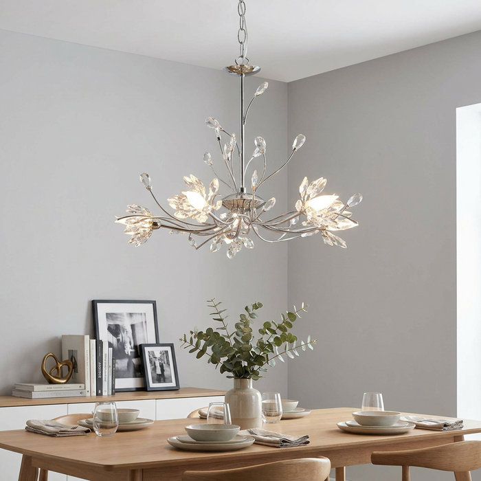 Hibiscus 5 light chrome and crystal floral pendant hanging over a modern dining table in a neutral room.