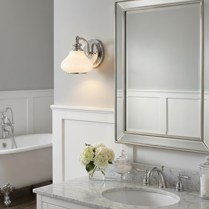 Ainsley 1-light polished chrome wall sconce with a white glass shade mounted next to a bathroom mirror.