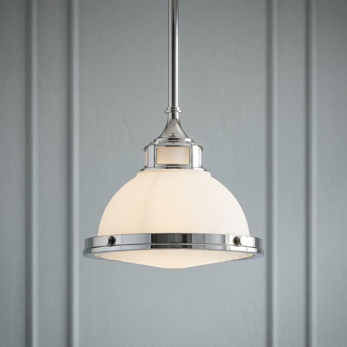 Hinkley Amelia small Art Deco pendant light with chrome finish and frosted white glass dome against a paneled wall.
