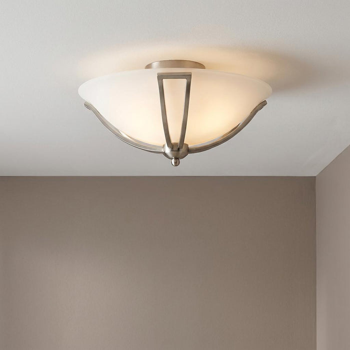 Hinkley Bolla brushed nickel flush ceiling light with an opal glass bowl shade glowing on a white ceiling.