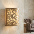 Hinkley Carabel wall light featuring ornate gold scrollwork and an ivory diffuser on a textured neutral wall.