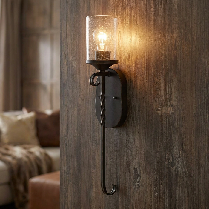 Hinkley Casa black wall light with seeded glass and twisted iron stem on a rustic wood paneled wall.