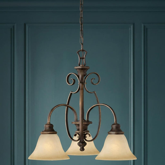 Antique bronze three-light chandelier with cream glass bell shades and scrollwork against a teal paneled wall.
