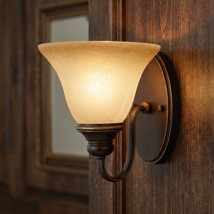Antique bronze wall light with a frosted glass bell shade mounted on dark wood paneling.