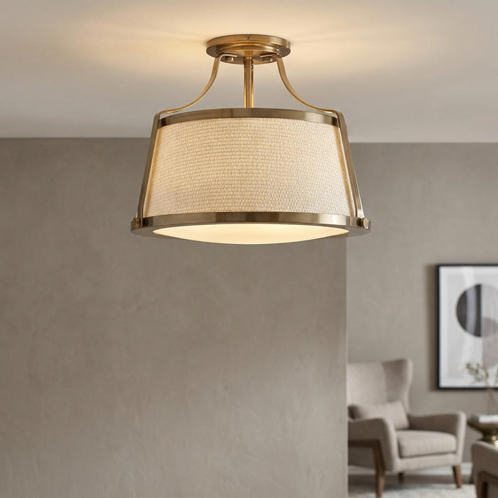Hinkley Charlotte antique brass semi-flush ceiling light with a textured drum shade in a modern living room.