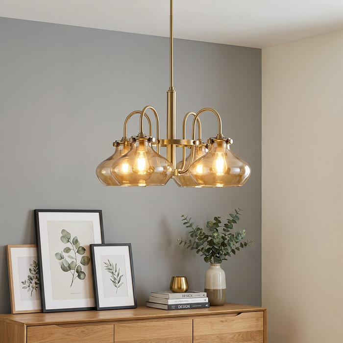 Four-light chandelier in brushed caramel with amber glass shades hanging above a wooden sideboard in a modern room.