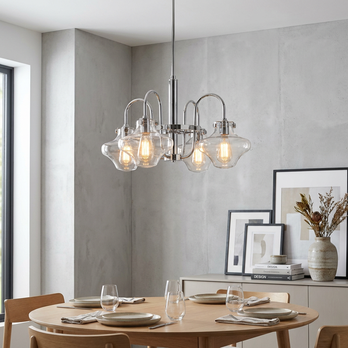 Chrome 4-light chandelier with clear glass shades and Edison bulbs hanging above a set dining table.