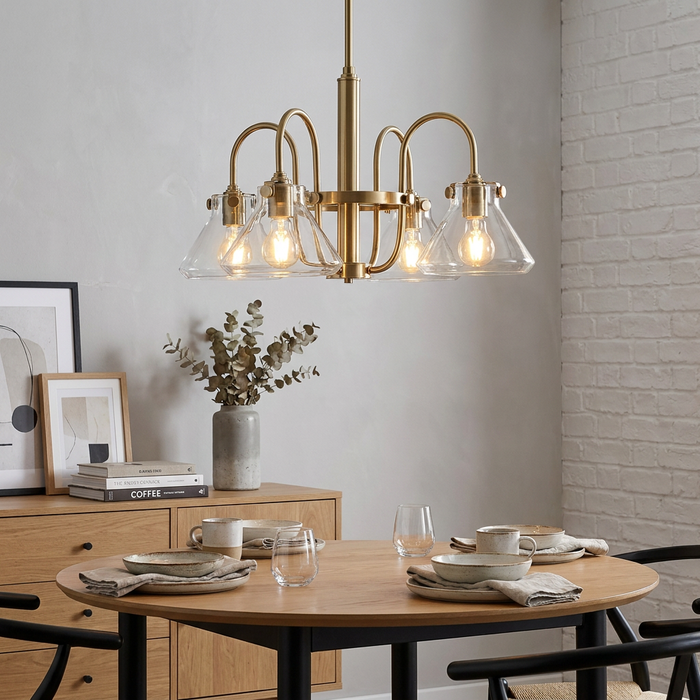 Brushed caramel chandelier with clear glass shades hanging over a wooden dining table in a modern interior.