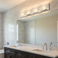 Four-light polished chrome vanity fixture with seeded glass shades mounted above a bathroom mirror.