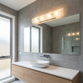 Hinkley Duet 4-light wall light above a bathroom mirror in a modern tiled room with a wood vanity.