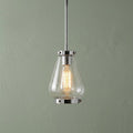 Hinkley Finley mini pendant light in chrome with a seeded glass shade and glowing Edison bulb against a green wall.