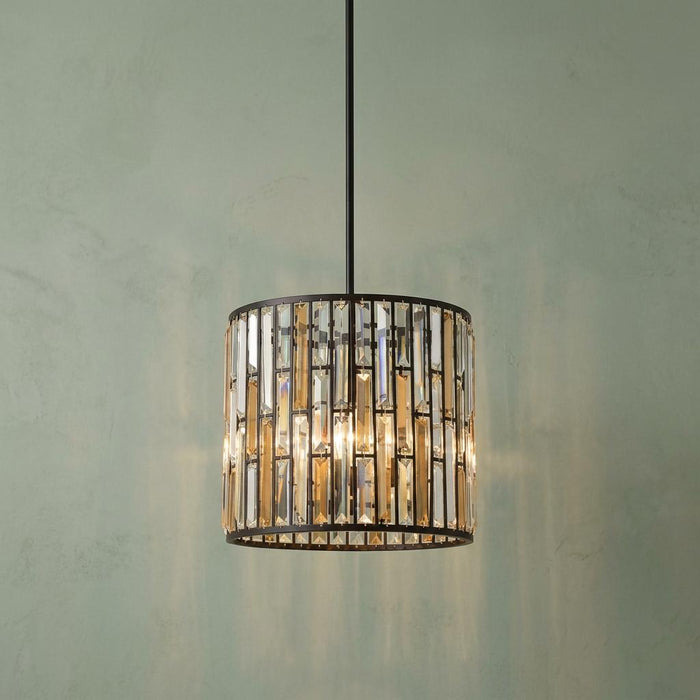 A Hinkley Gemma bronze pendant light with amber and clear crystal prisms against a pale green wall.