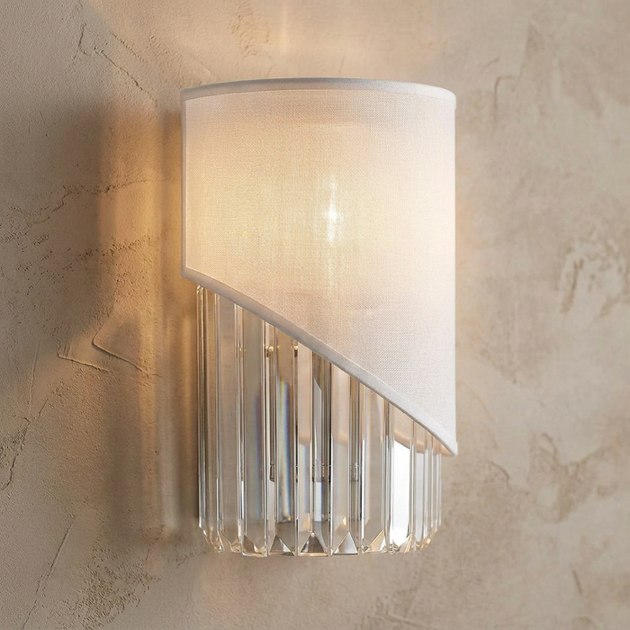 Modern wall light with a white fabric half-shade and vertical crystal prisms mounted on a textured beige wall.