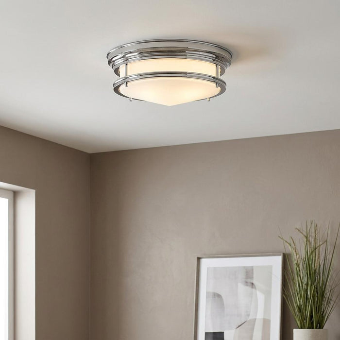 Art Deco chrome flush mount ceiling light with a frosted glass shade illuminated in a neutral room.