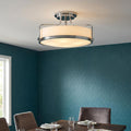 Polished chrome semi-flush ceiling light with opal drum shade illuminating a dining room with teal wallpaper.