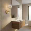 Hinkley Hollis brass wall light with a seeded glass globe mounted on a stone tile wall in a modern bathroom.