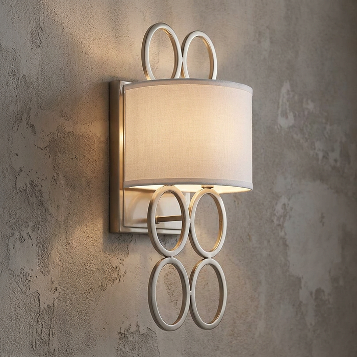 Jules two-light nickel wall sconce with a white shade and interlocking rings on a textured gray wall.
