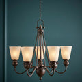A six-light Olde Bronze chandelier with frosted glass shades set against a dark teal wall.