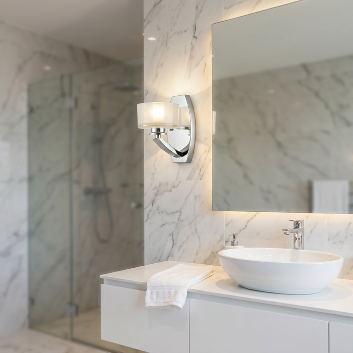 Hinkley Meridian chrome wall light with frosted glass shade mounted on a marble bathroom wall beside a vanity mirror.