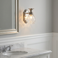 Pineapple-shaped polished nickel bathroom wall light mounted on a gray wall above a marble vanity.