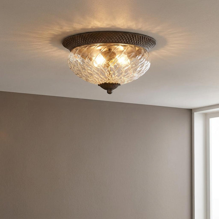 Hinkley Plantation bronze flush ceiling light with pineapple-patterned glass shade casting light onto a white ceiling.