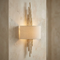 Hinkley Spyre champagne gold wall light with a textured branch design and cream shade on a plaster wall.