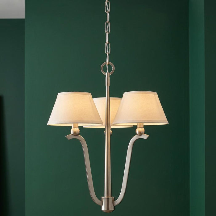 Hinkley Whitney 3-light chandelier in brushed nickel with fabric shades against a dark green wall.